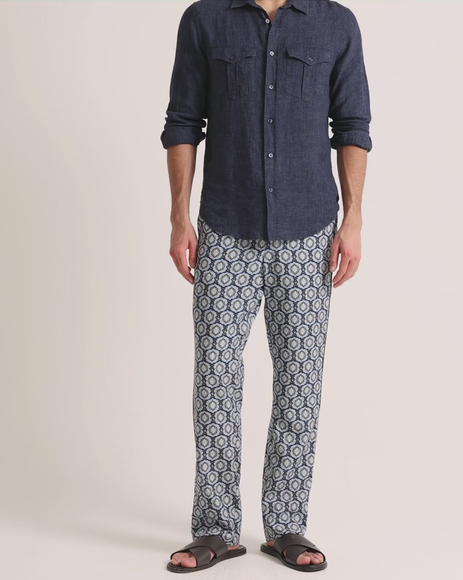Man wearing printed blue trousers with navy linen shirt on a plain background