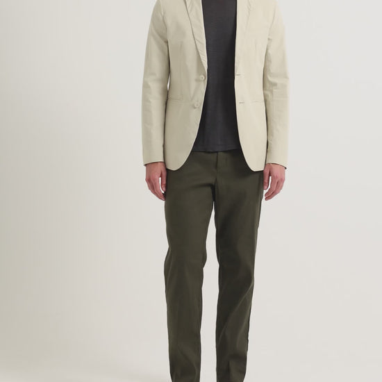 Man wearing light beige blazer with dark navy t-shirt and dark green trousers