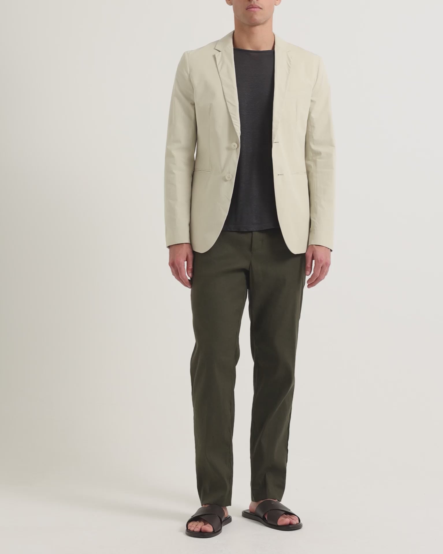 Man wearing light beige blazer with dark navy t-shirt and dark green trousers