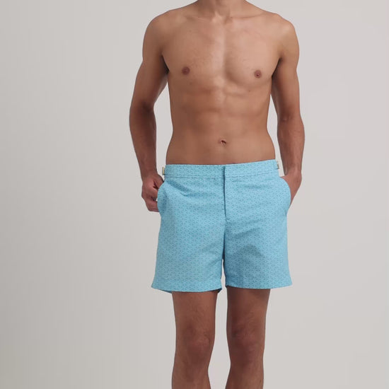 Man wearing blue printed swim shorts on a plain background