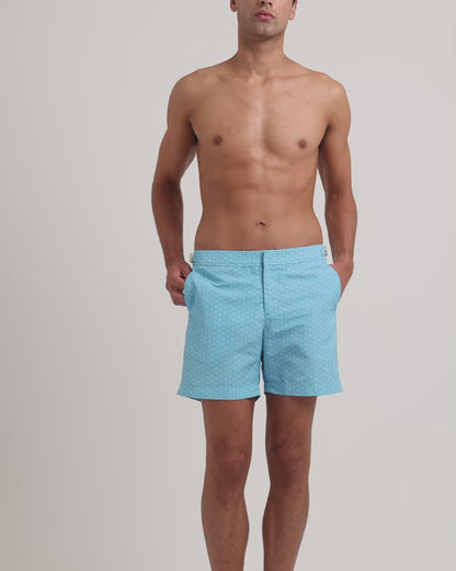 Man wearing blue printed swim shorts on a plain background