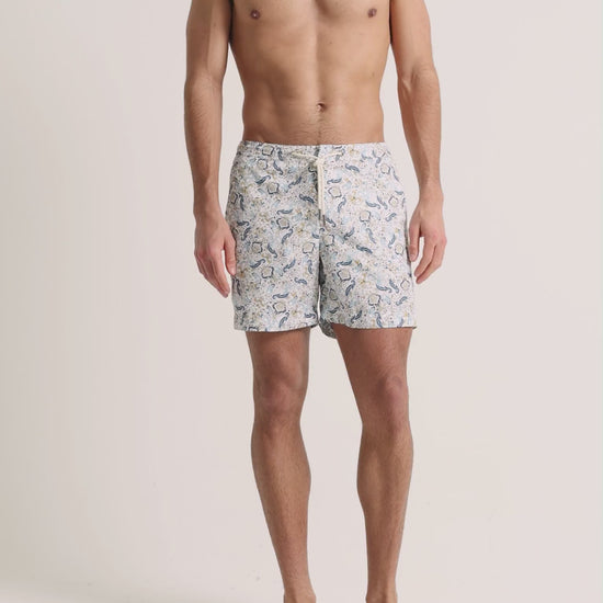 Man wearing blue printed drawcord swim shorts on a plain background