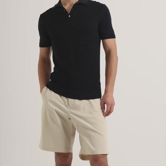 Man wearing dark navy polo shirt with knee length beige shorts