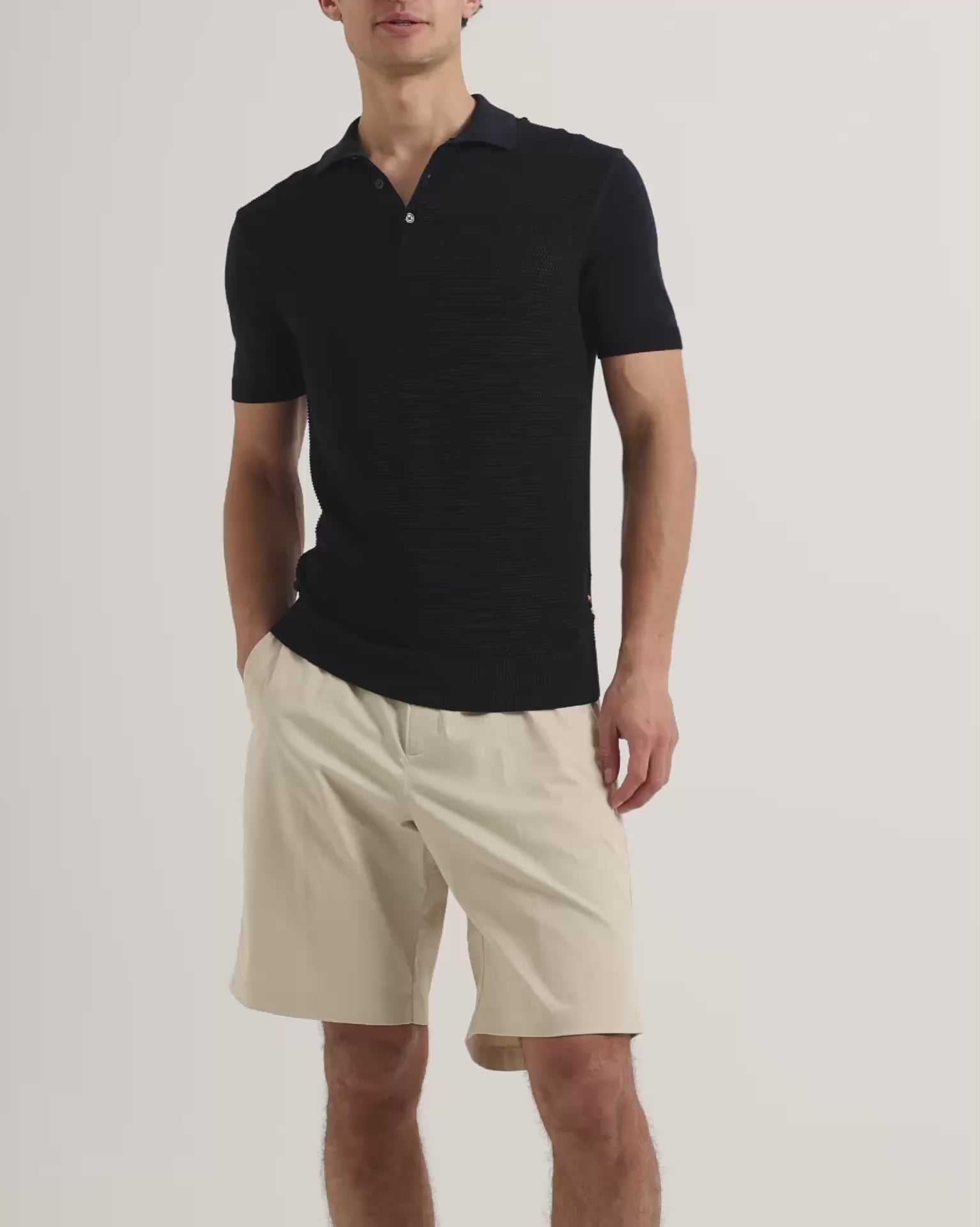 Man wearing dark navy polo shirt with knee length beige shorts
