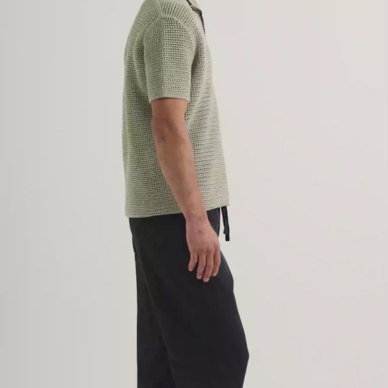 Man wearing light green crochet stitch polo shirt with navy drawstring trousers