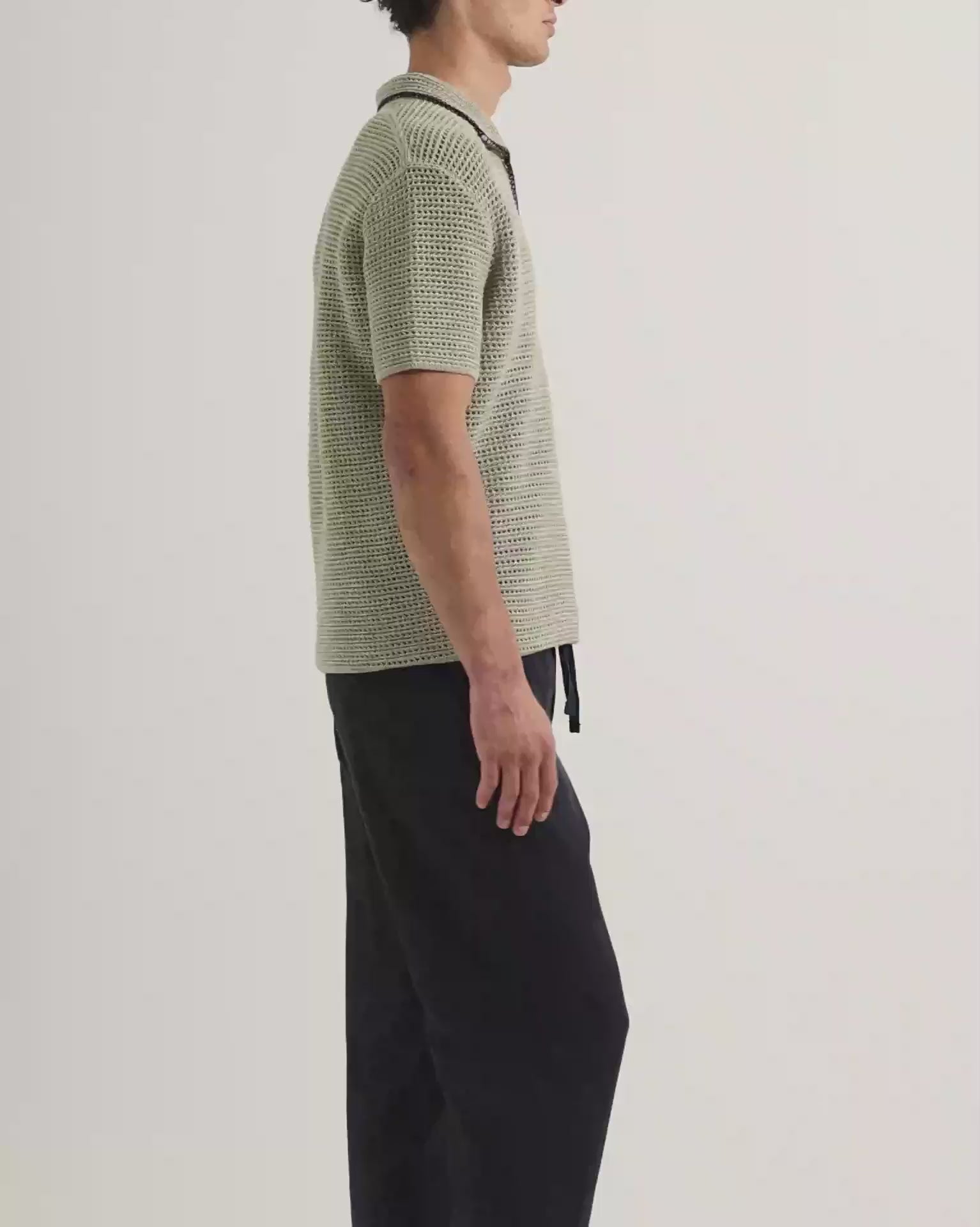 Man wearing light green crochet stitch polo shirt with navy drawstring trousers