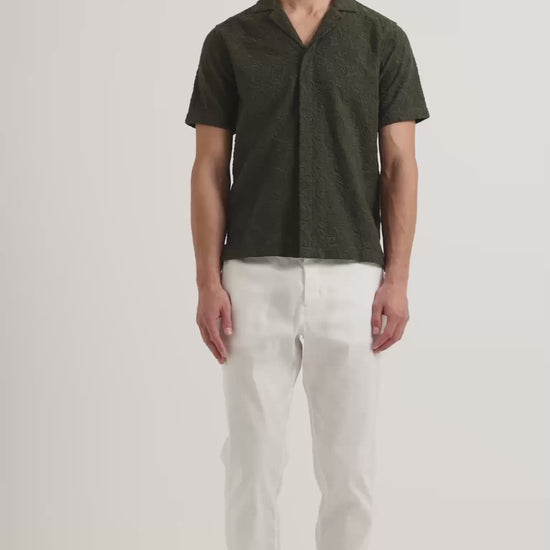 Man wearing dark green broderie anglaise shirt with white trousers