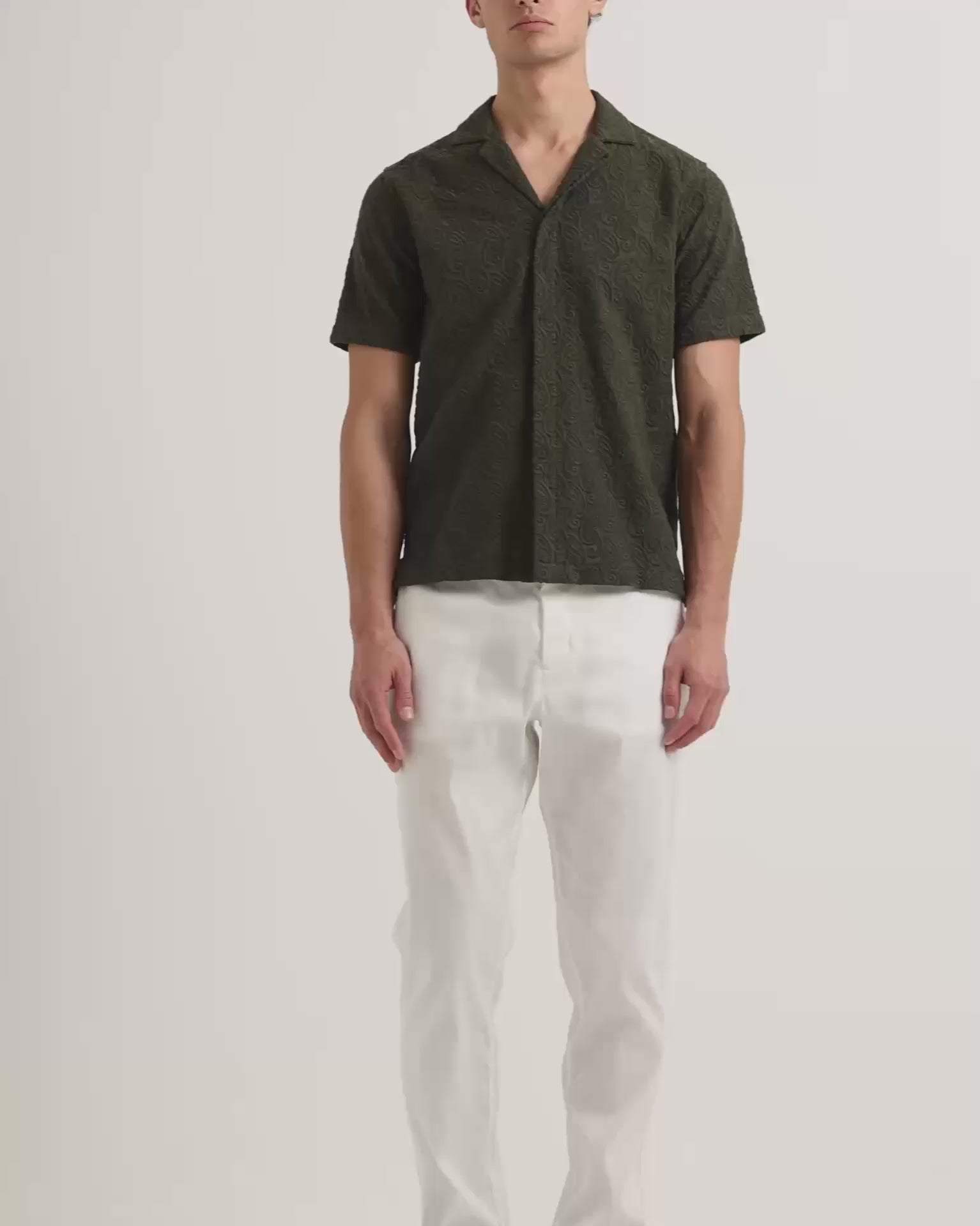 Man wearing dark green broderie anglaise shirt with white trousers
