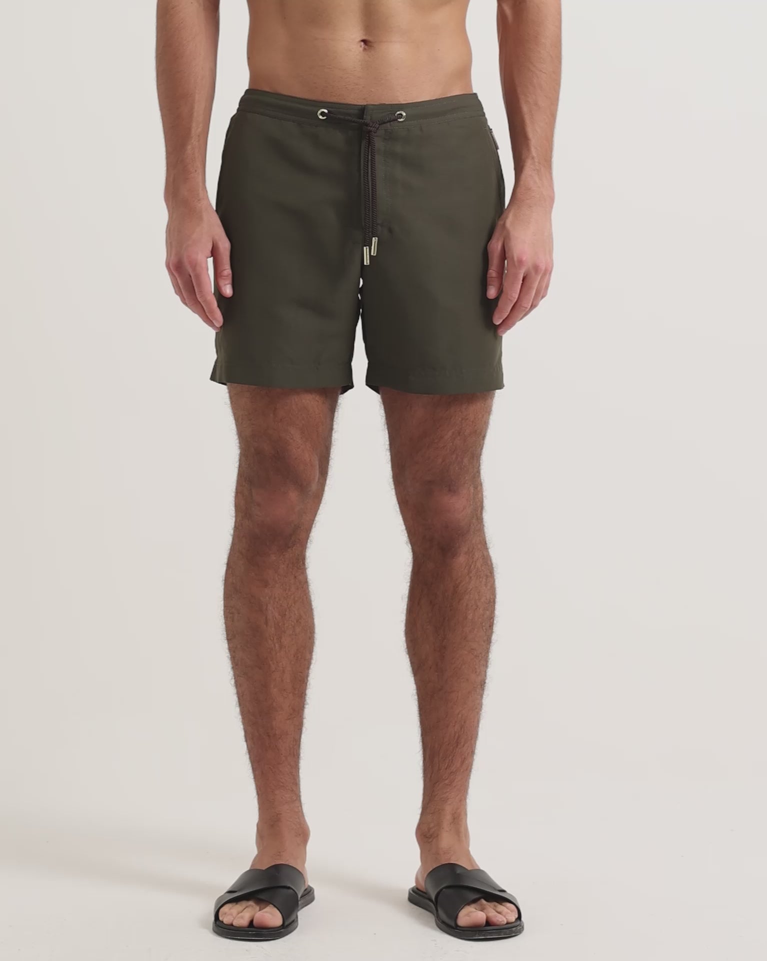 Model wearing dark green drawcord swim shirts with brown leather sandals