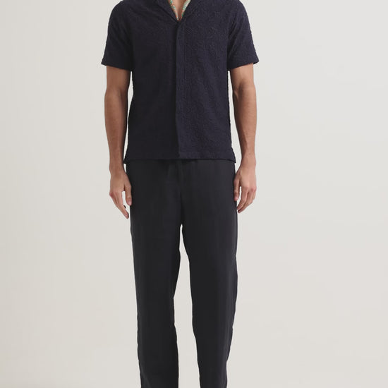 Man wearing navy broderie anglaise shirt with dark navy trousers