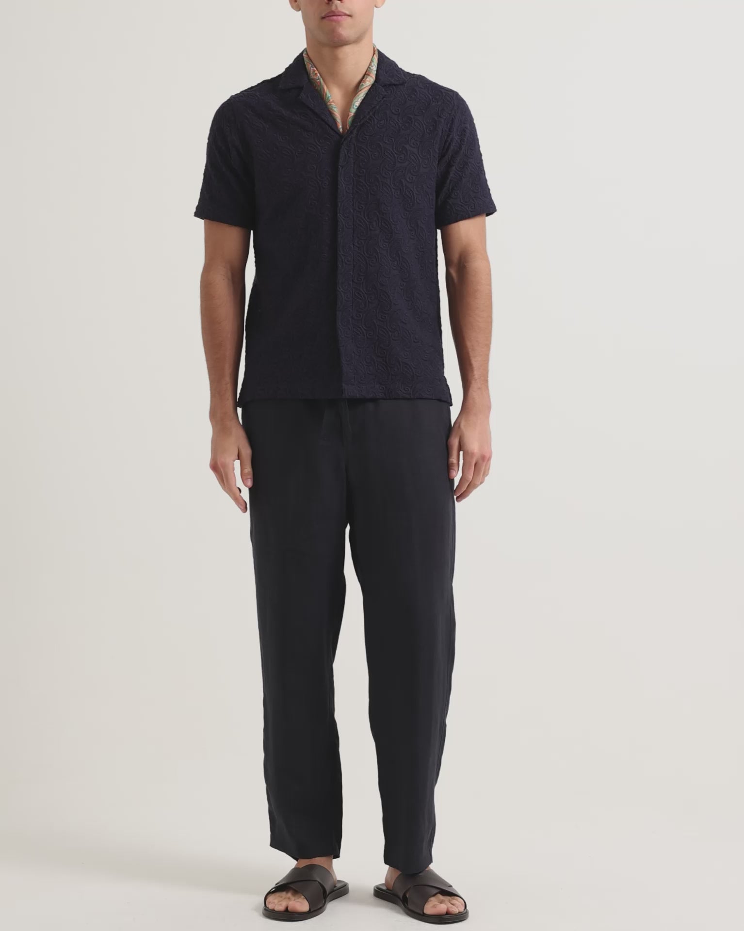 Man wearing navy broderie anglaise shirt with dark navy trousers