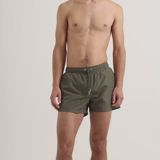 Man wearing dark green swim shorts with drawstring waist