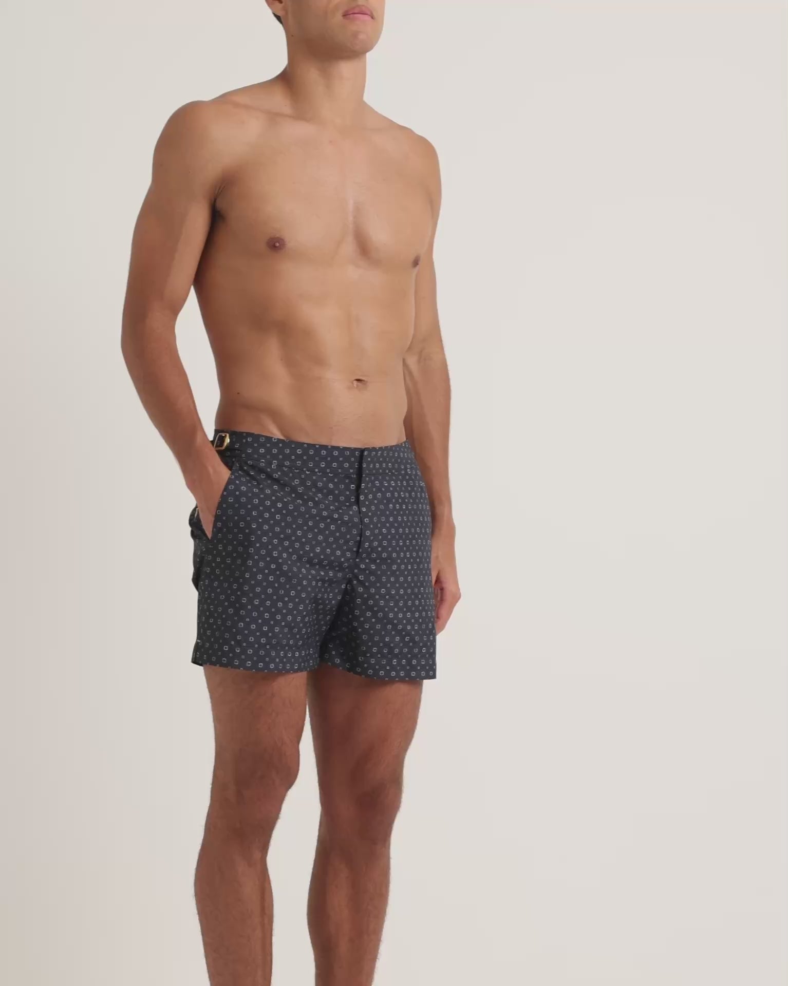 Man wearing navy geometric print swim shorts on a plain background