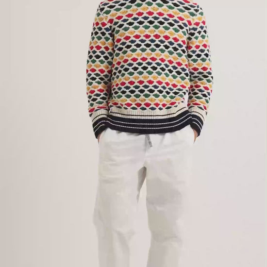 Man wearing multicolour crochet stitch hoodie with white trousers
