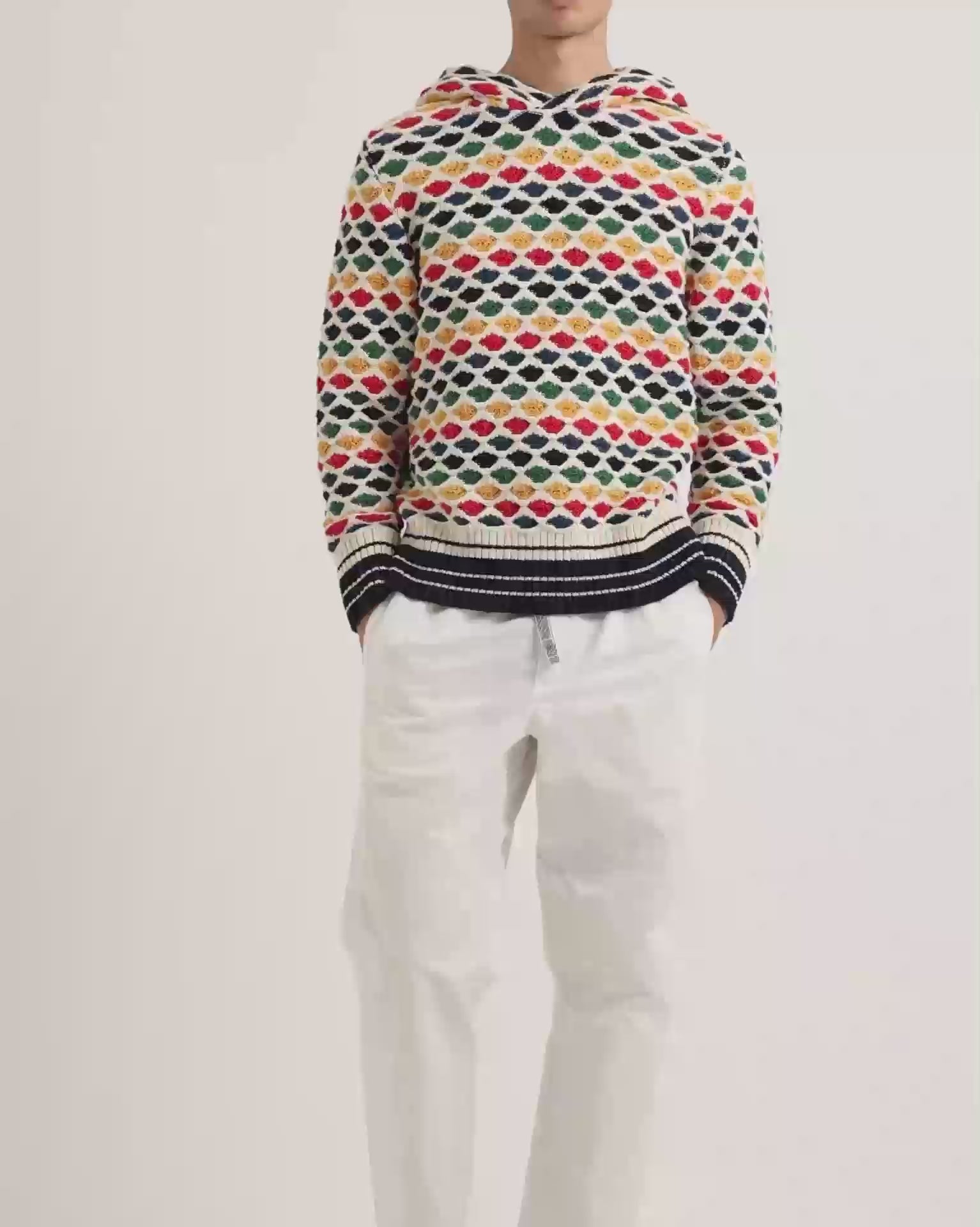 Man wearing multicolour crochet stitch hoodie with white trousers