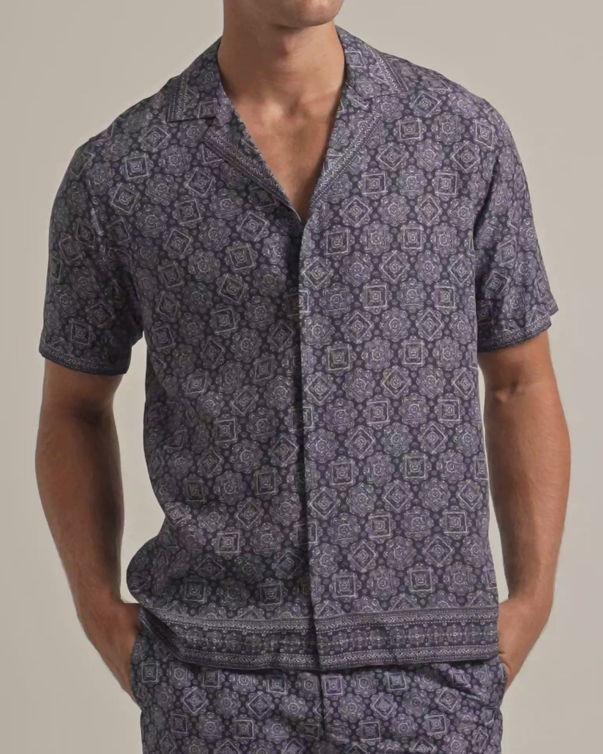 Man wearing navy and white geometric print shirt with matching swim shorts against a plain background