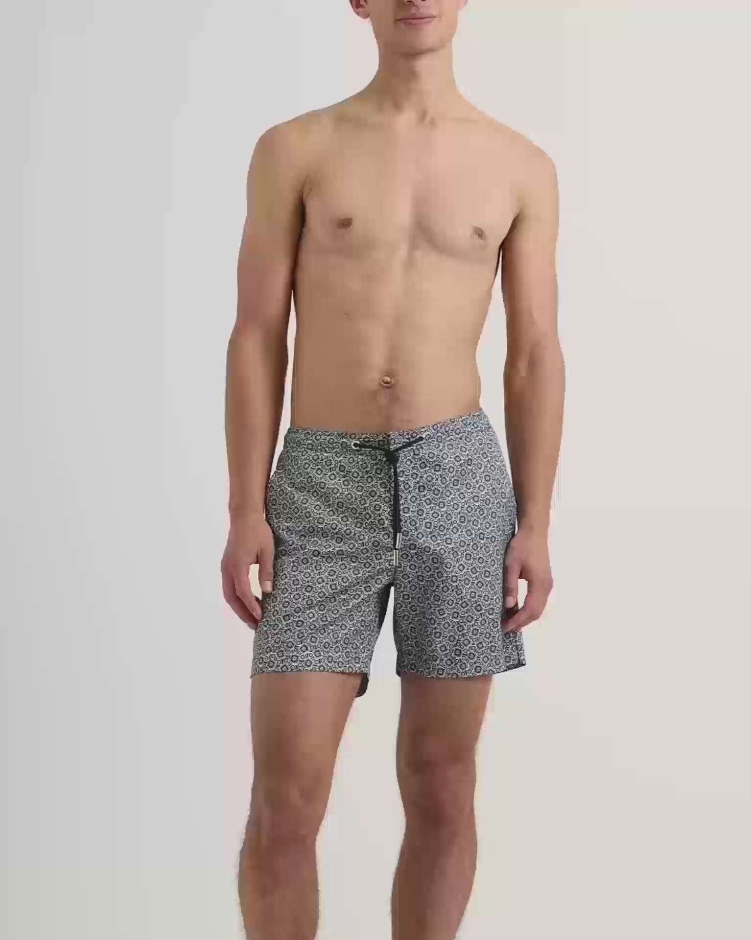 Man wearing dark navy patterned swim shorts with drawstring waist