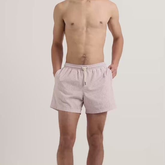 Man wearing seersucker striper swim shorts in red