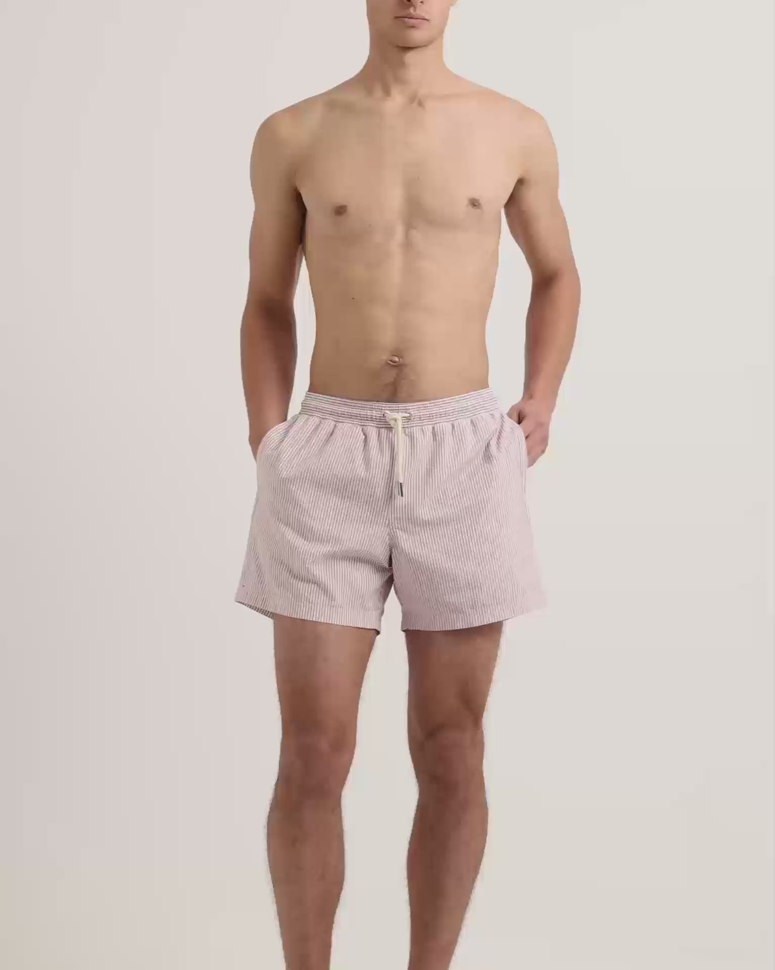 Man wearing seersucker striper swim shorts in red