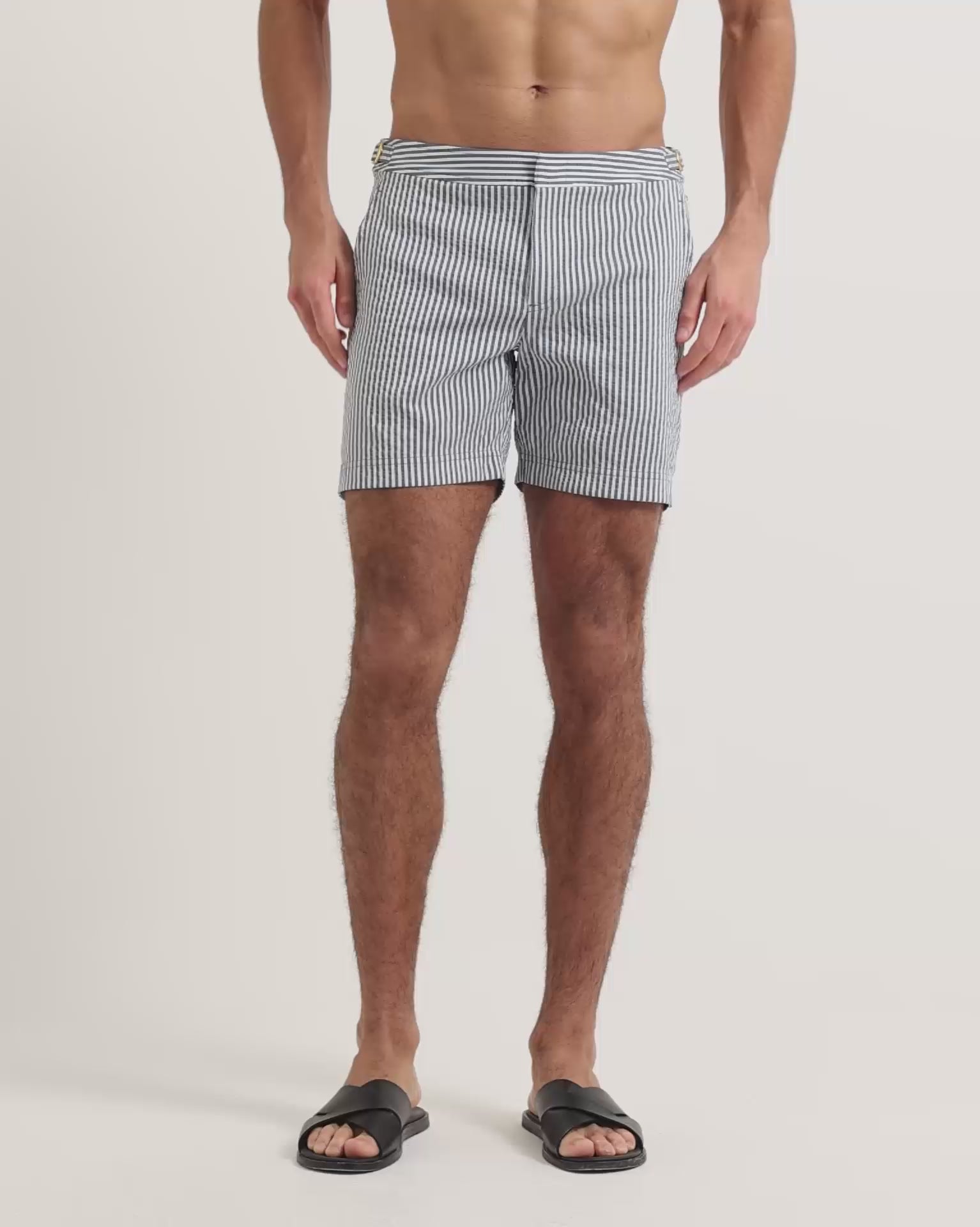 Man wearing blue and white striped swim shorts with brown leather sandals