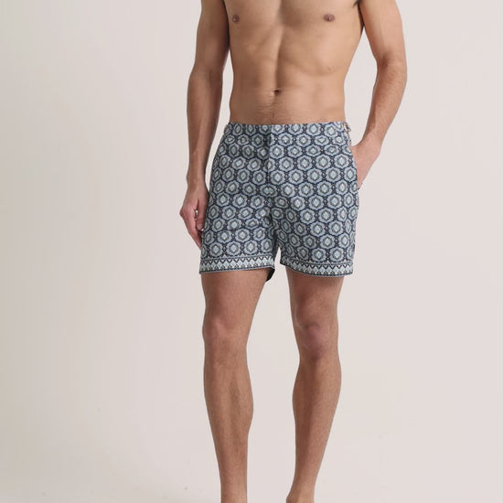 Man wearing blue printed swim shorts on a plain background