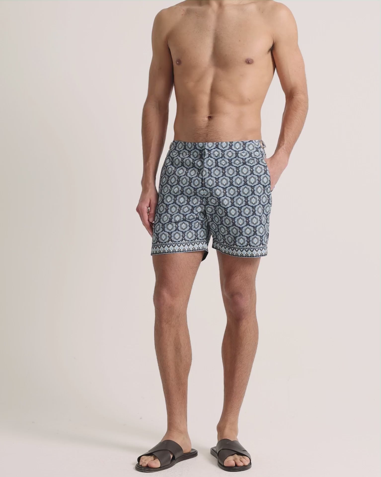 Man wearing blue printed swim shorts on a plain background