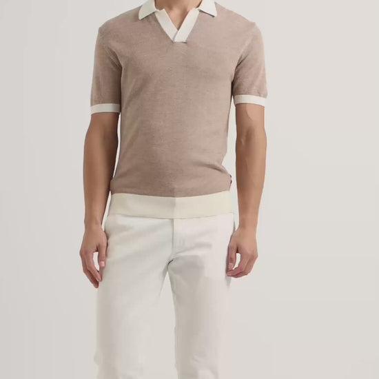 Man wearing beige polo shirt with white contrast tipping and white trousers
