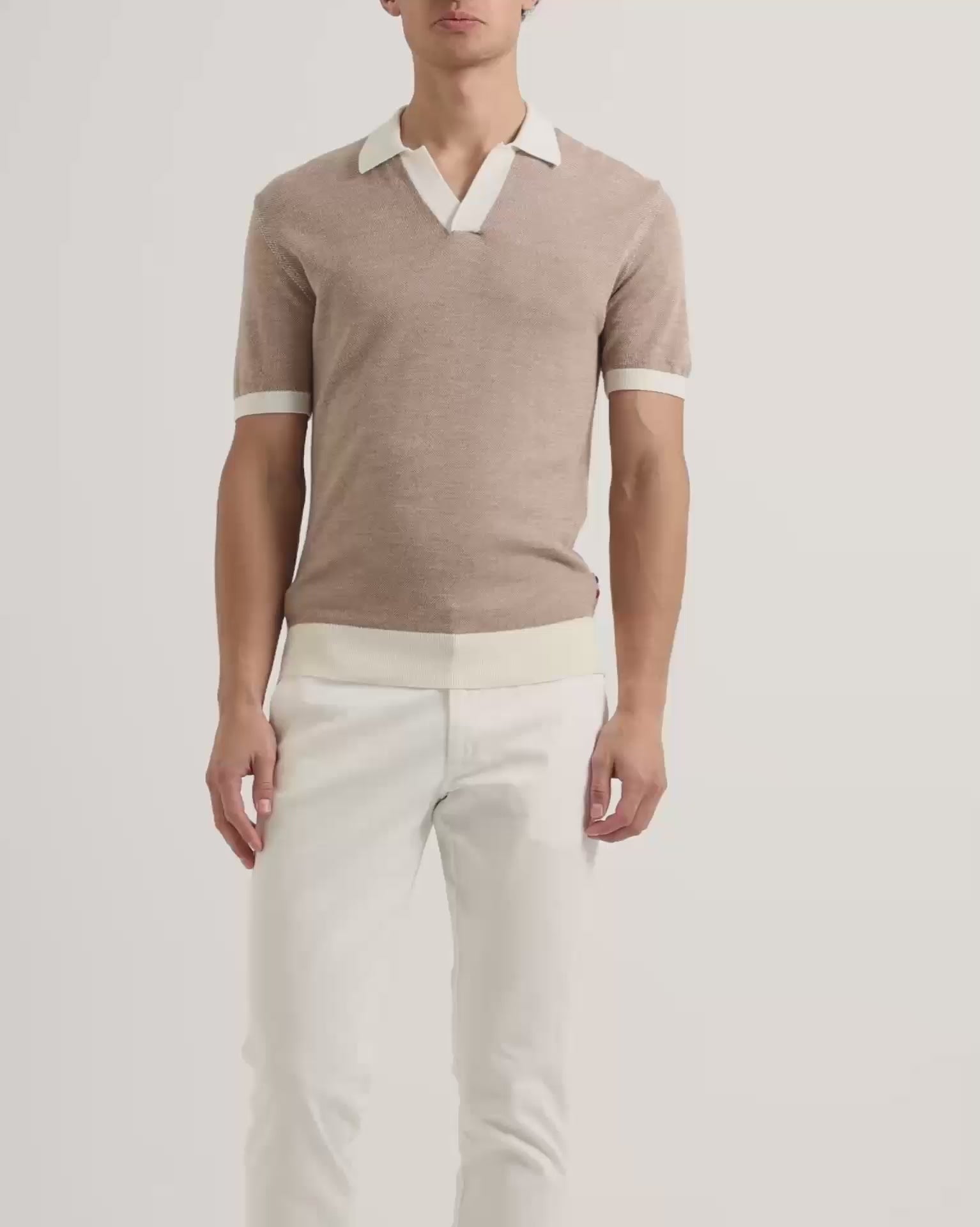 Man wearing beige polo shirt with white contrast tipping and white trousers