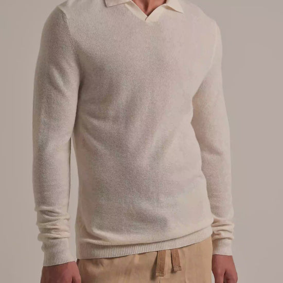 Man wearing white knitted cashmere jumper with beige trousers on a white background
