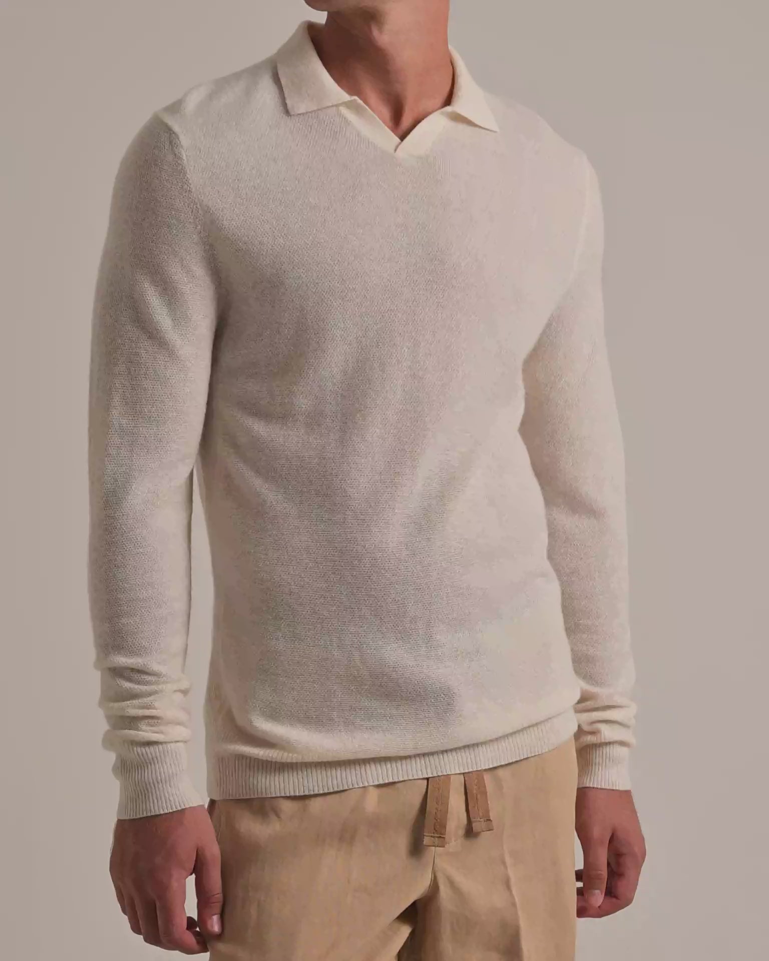 Man wearing white knitted cashmere jumper with beige trousers on a white background