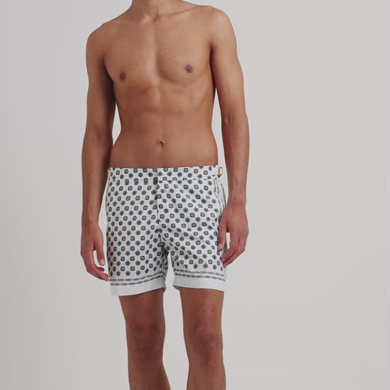 Man wearing white patterned swim on a plain background