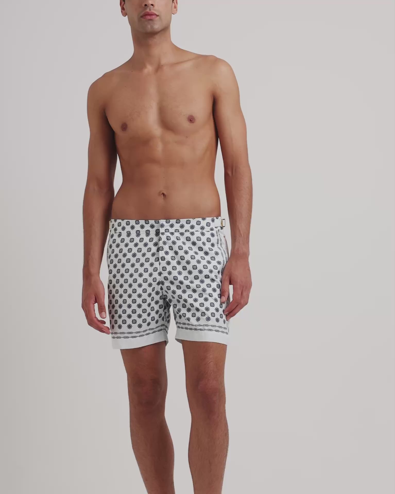 Man wearing white patterned swim on a plain background