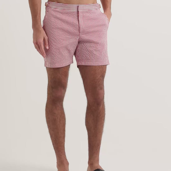 Man wearing red and white striped swim shorts with brown leather sandals
