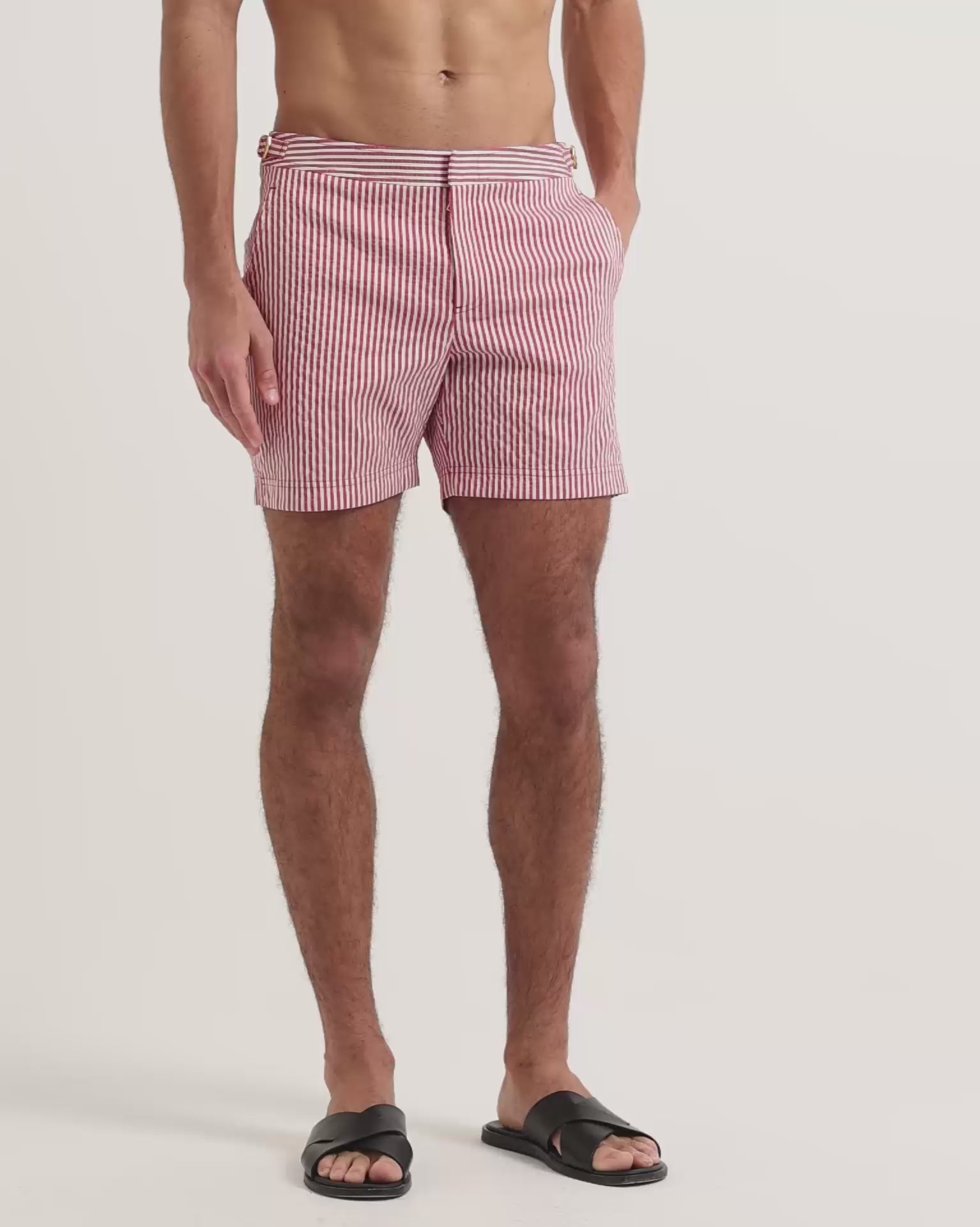 Man wearing red and white striped swim shorts with brown leather sandals