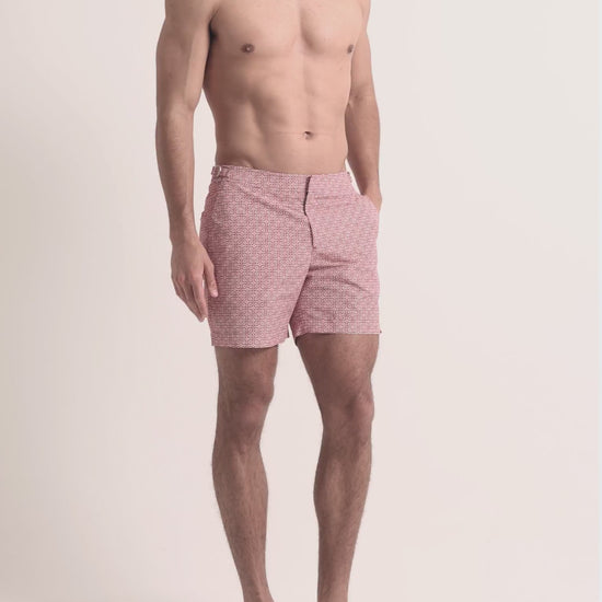 Man wearing red printed swim shorts on a plain background