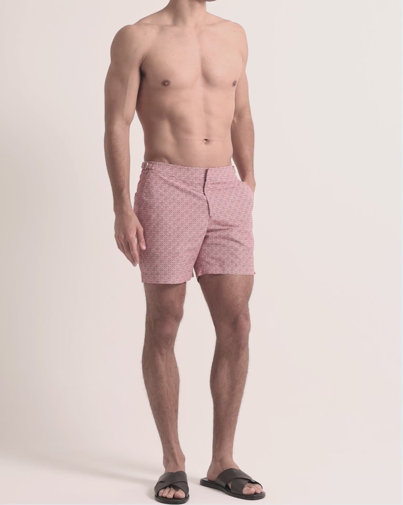 Man wearing red printed swim shorts on a plain background