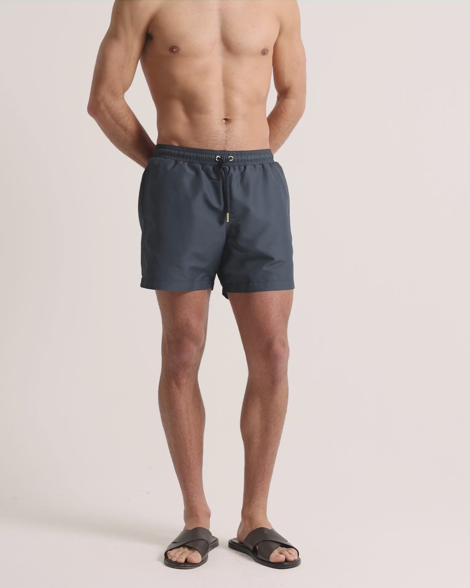 Man wearing grey swim shorts on a plain background