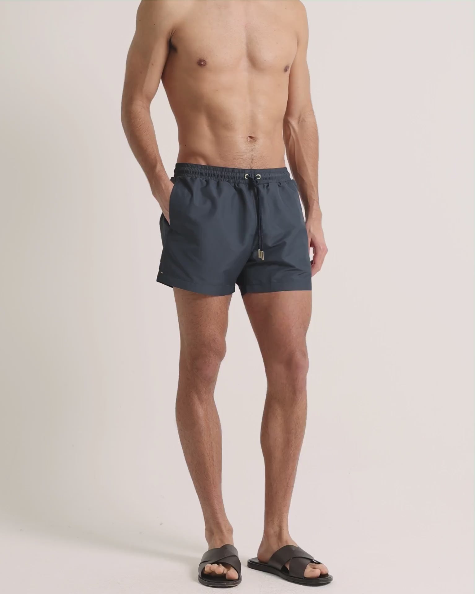 Man wearing grey swim shorts on a plain background