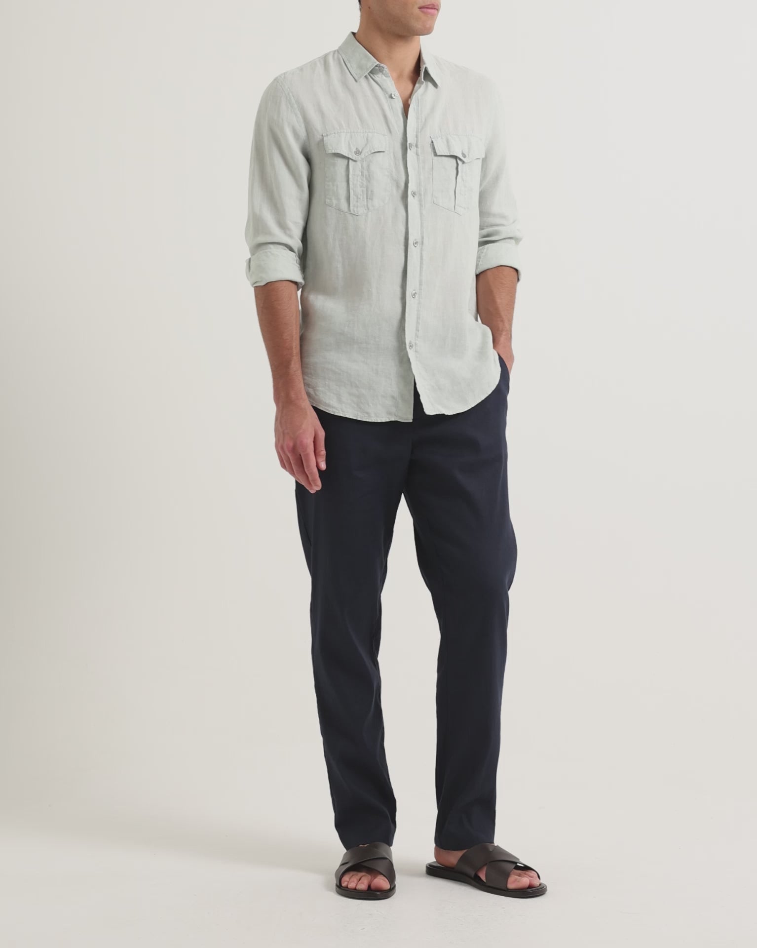 Man wearing Ray linen navy tailored trousers with pale blue shirt with chest pockets