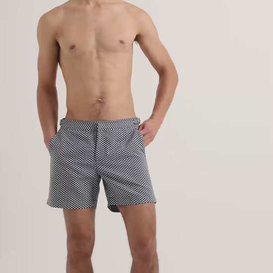 Man wearing navy and white patterned swim shorts with dark brown leather sandals 