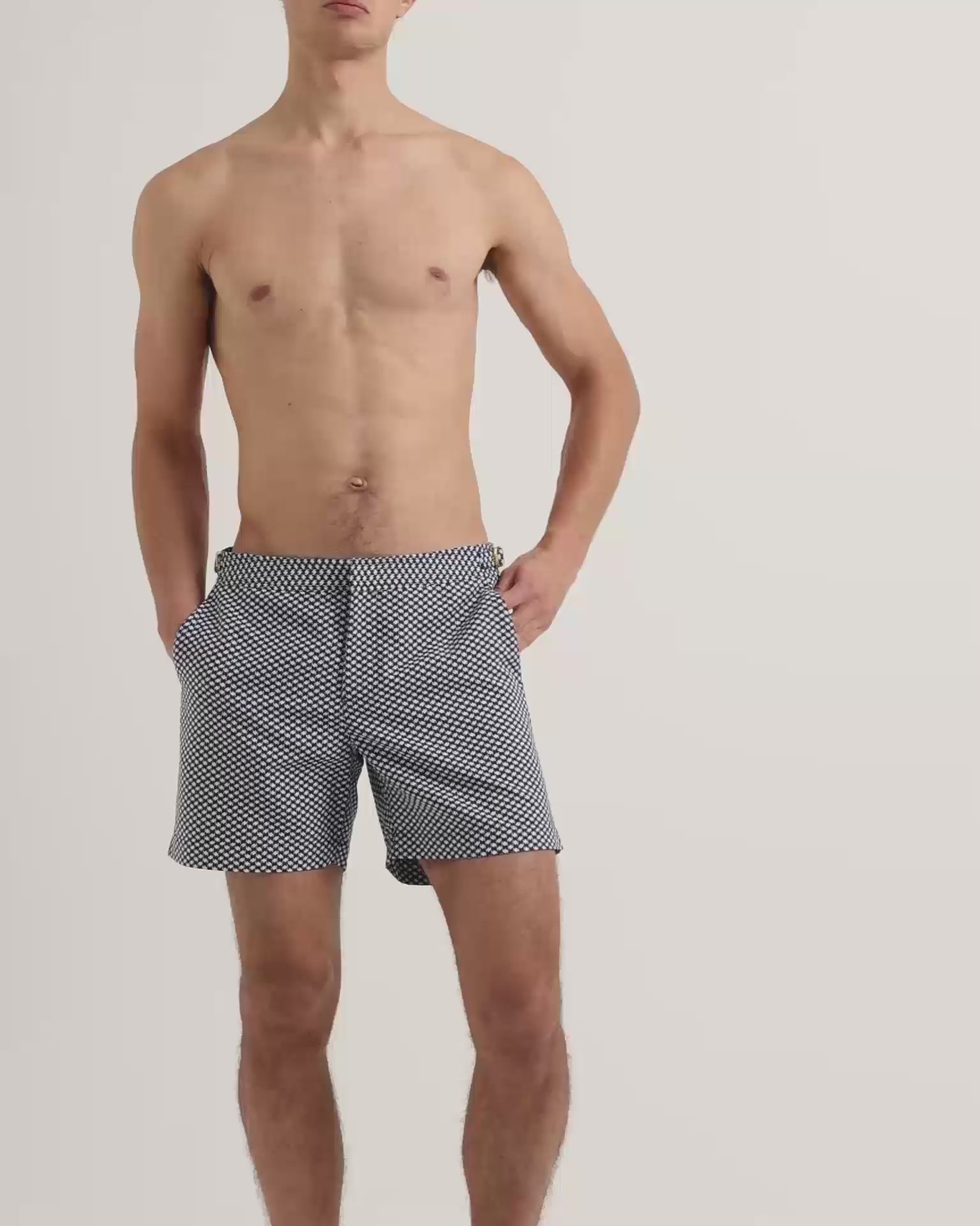 Man wearing navy and white patterned swim shorts with dark brown leather sandals 