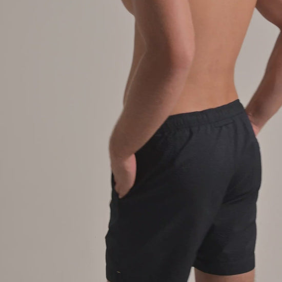 Man wearing brown seersucker swim shorts against a plain background