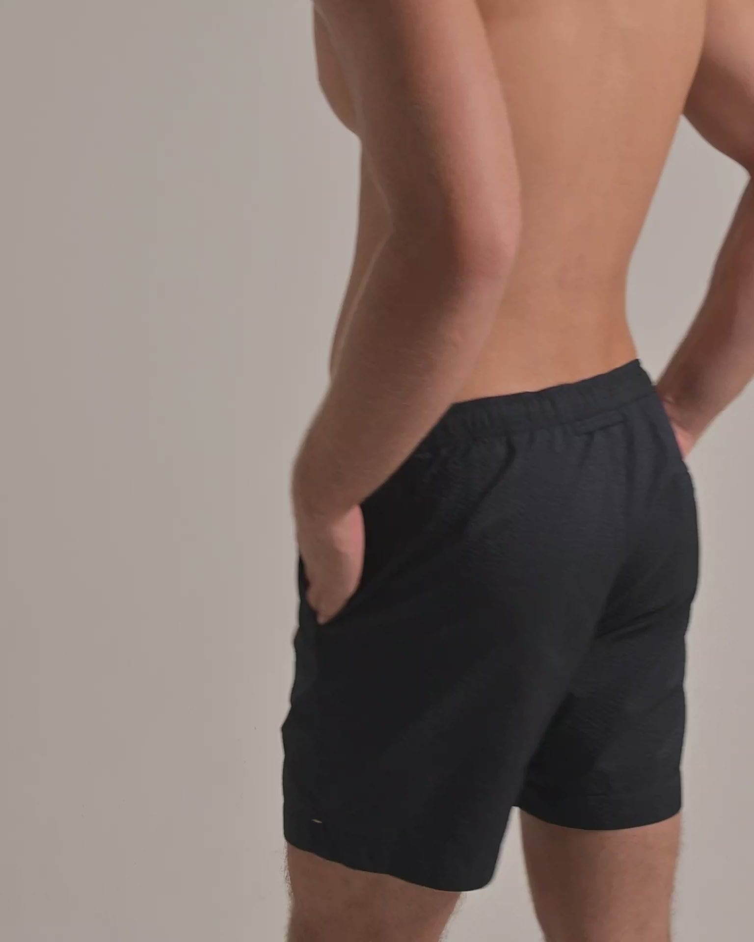 Man wearing brown seersucker swim shorts against a plain background