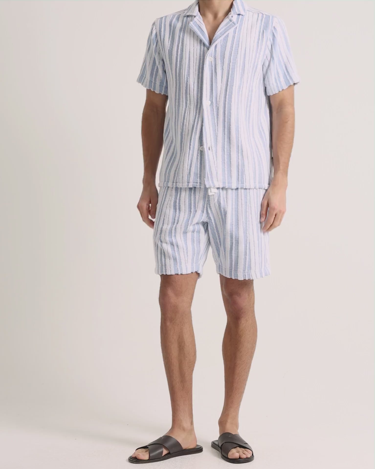 Man wearing blue striped towelling set on a white background