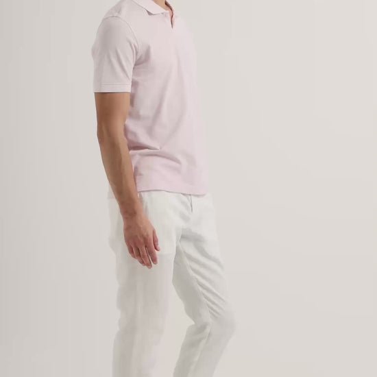 Man wearing light pink polo shirt with white trousers