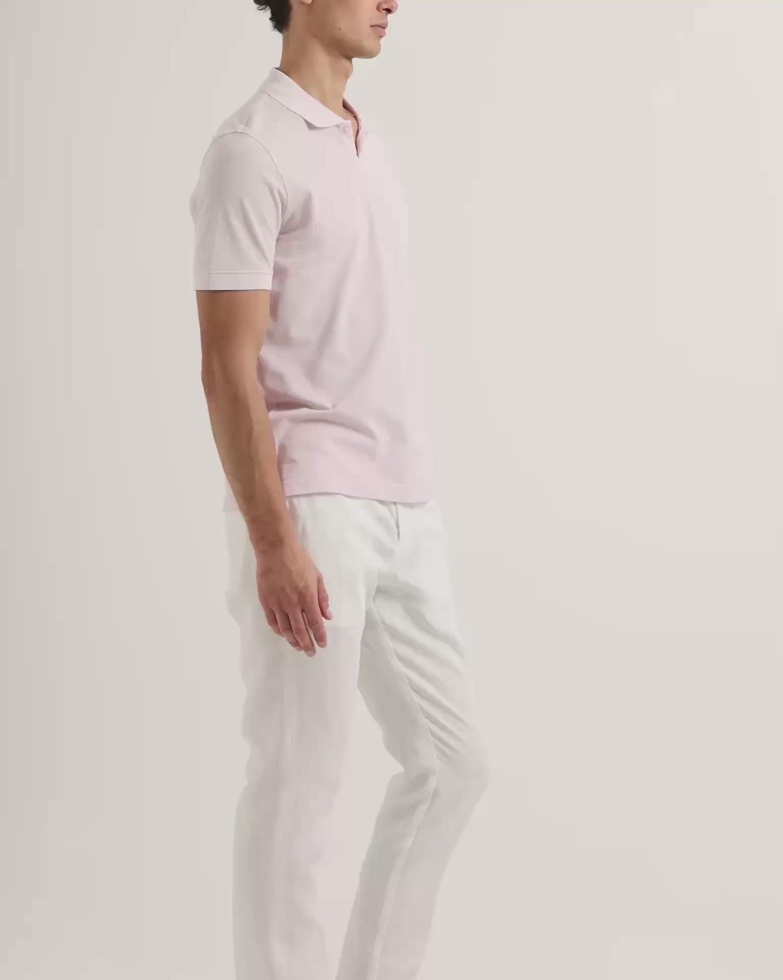 Man wearing light pink polo shirt with white trousers