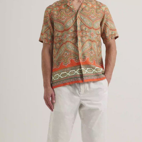 Video of model wearing printed short sleeve shirt with white trousers
