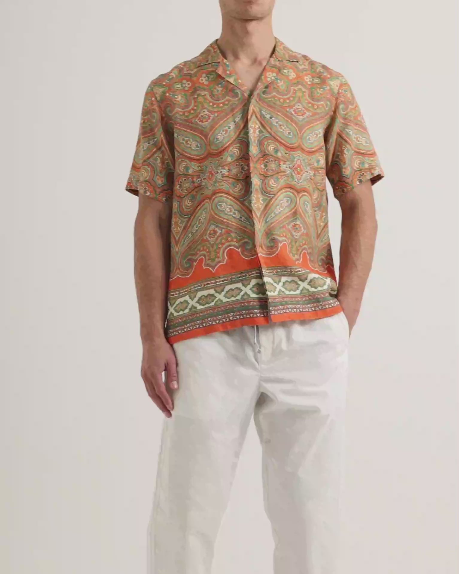 Video of model wearing printed short sleeve shirt with white trousers