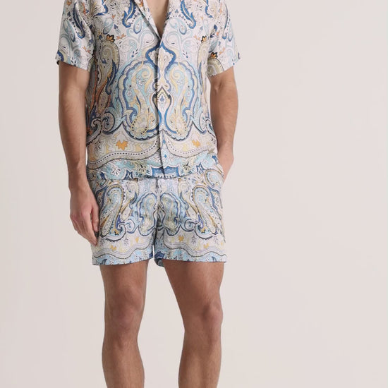 Man wearing printed blue shirt with matching shorts on a plain background