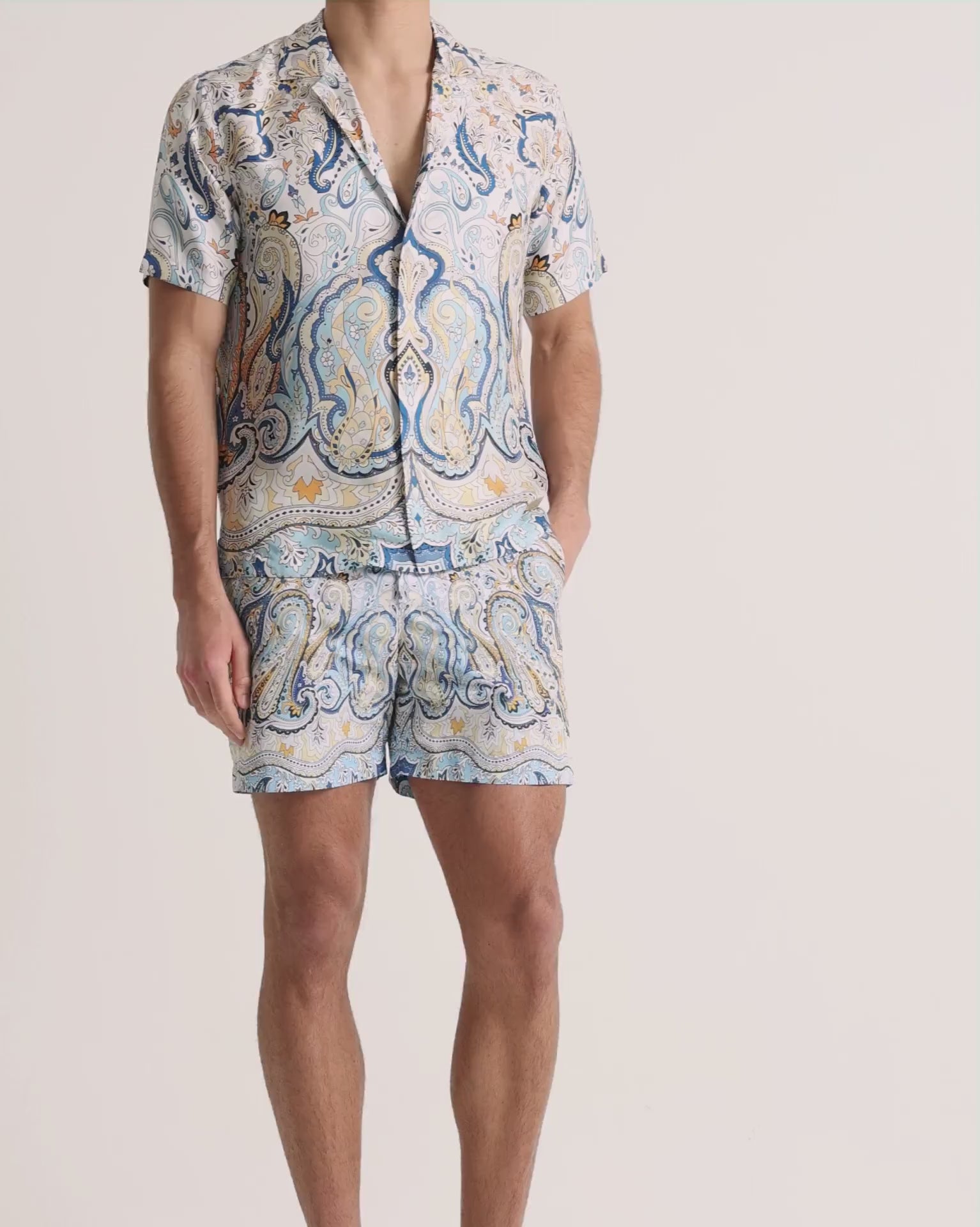 Man wearing printed blue shirt with matching shorts on a plain background